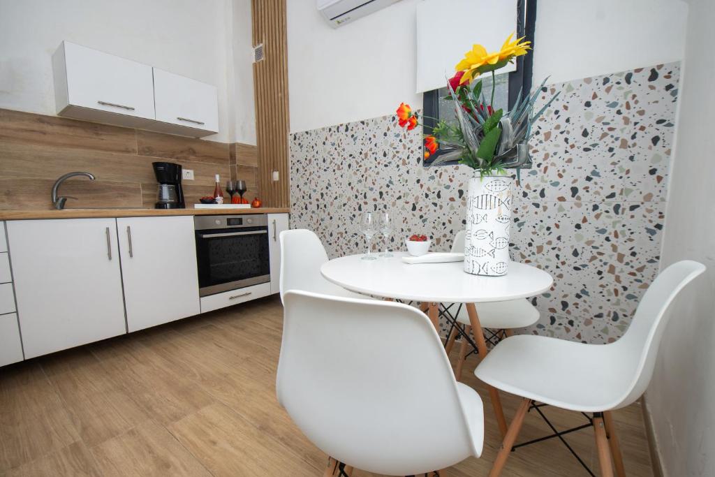 a kitchen with a table with white chairs and a vase with flowers at City house in Agios Rokkos