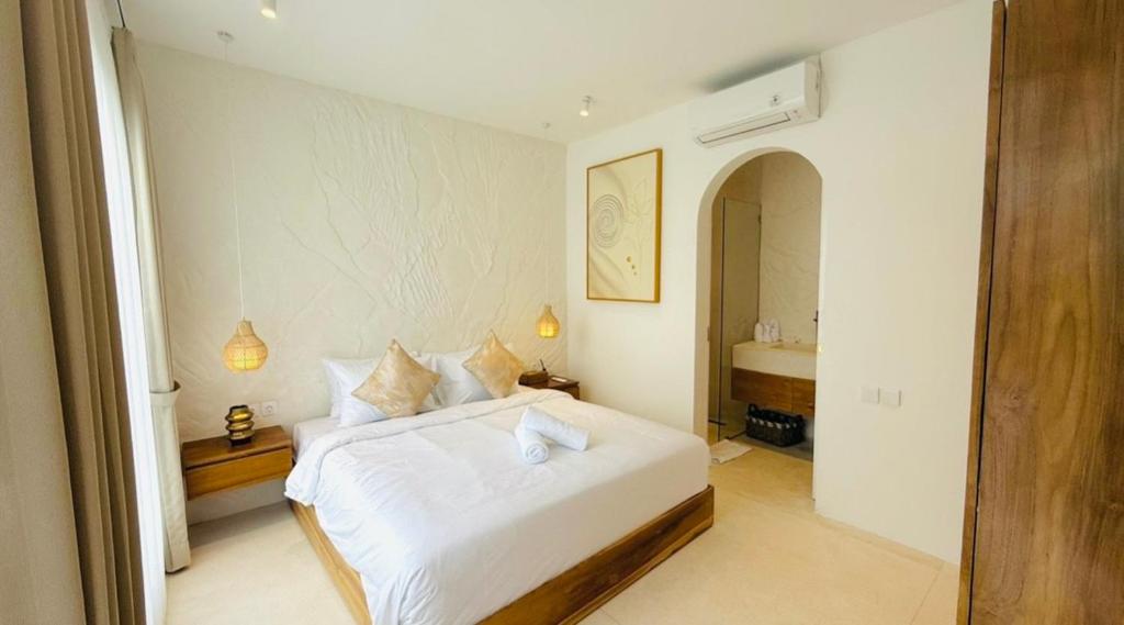 Un dormitorio con una cama blanca y un baño. en Bali Tranquility Uluwatu 2Flb White, en Uluwatu