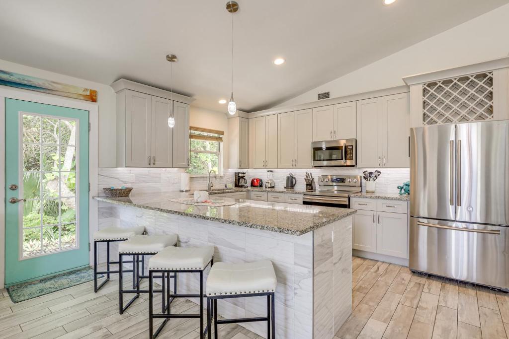 una cocina con armarios blancos y una gran isla con taburetes. en 1 Block to Beach, Patio Updated St Augustine Home, en St. Augustine