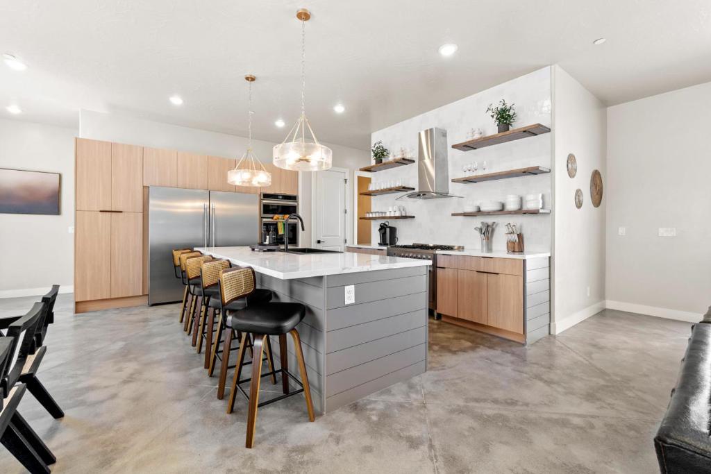 a kitchen with white cabinets and a bar with stools at Its about time, for adventure in Hurricane