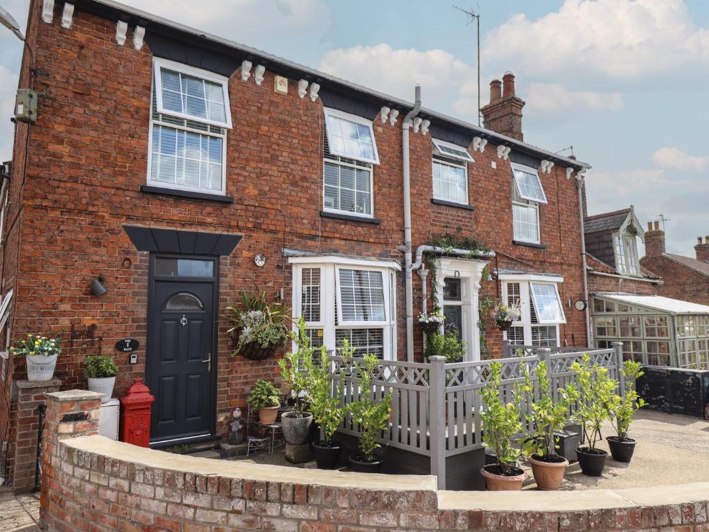 a brick house with a black door and potted plants at 1 The Bays in Skegness
