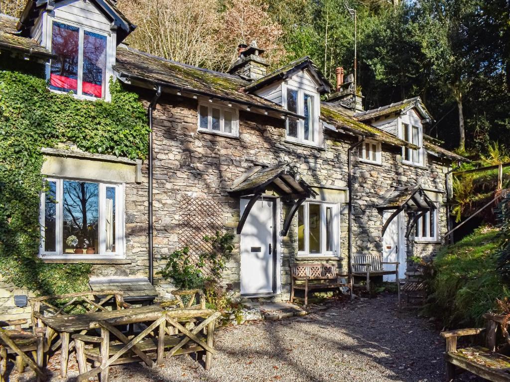 an old stone house with a bench in front of it at Tarn Cottage in Grasmere