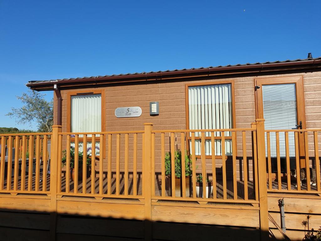 a house with a wooden deck with a fence at Trevella Lakeview Lodge in Newquay