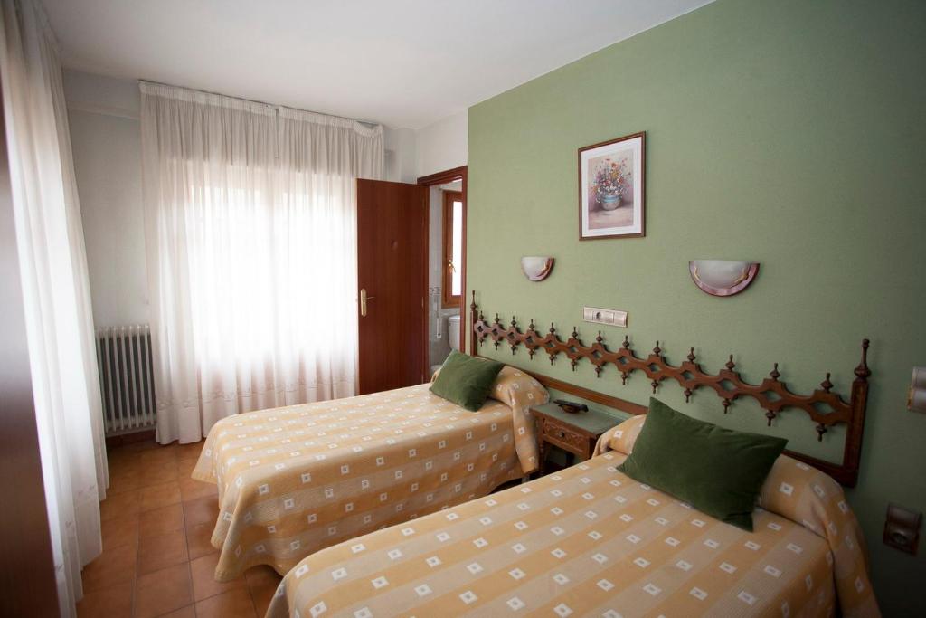 a hotel room with two beds and a couch at Hostal Aragon in Ejea de los Caballeros