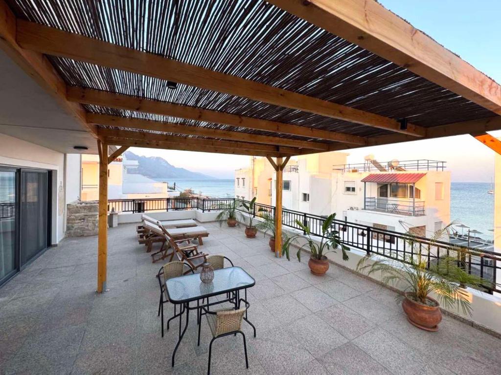 eine Terrasse mit Tischen und Stühlen auf einem Balkon in der Unterkunft Cecilia Sea View Apartment in Kardamena, Kos in Kardamaina