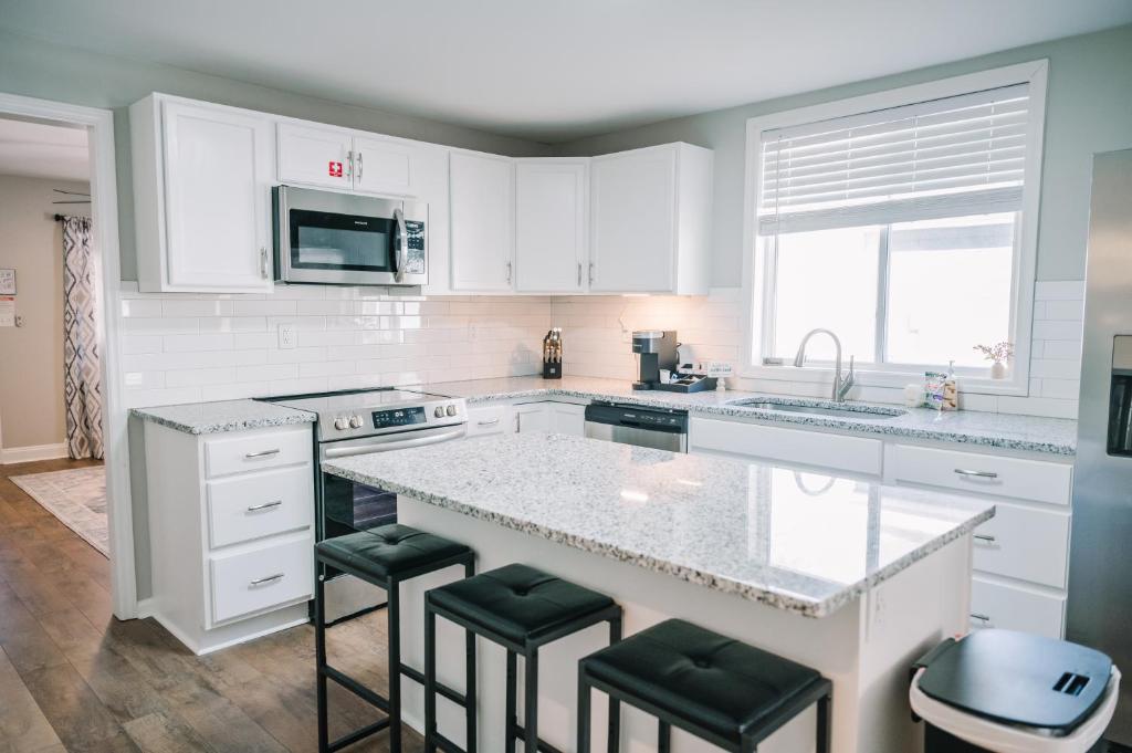 una cucina con mobili bianchi e un bancone con sgabelli di Avalon Cottage with hot tub a Danville