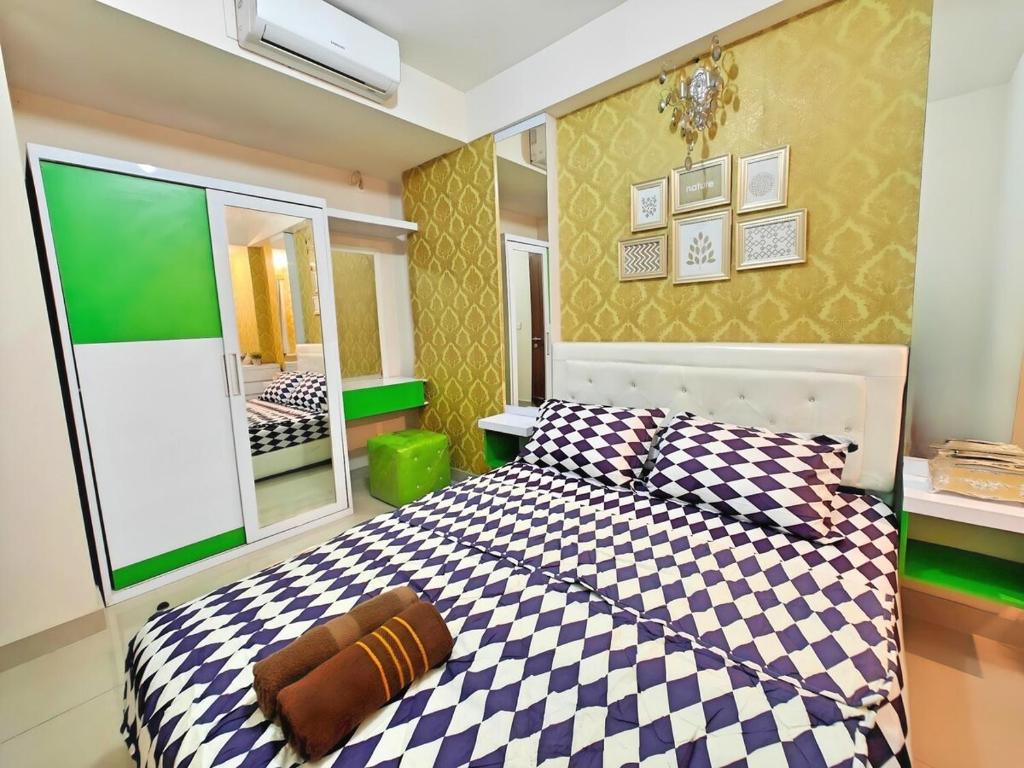a bedroom with a checkered bed and a mirror at Cozy 2BR Sudirman Suites Pool, Gym & WiFi in Bandung