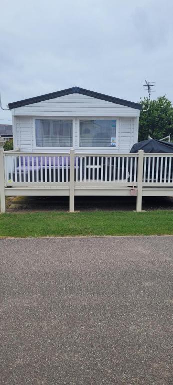 a white house with a white fence in front of it at Poppy Caravan in Leysdown-on-Sea