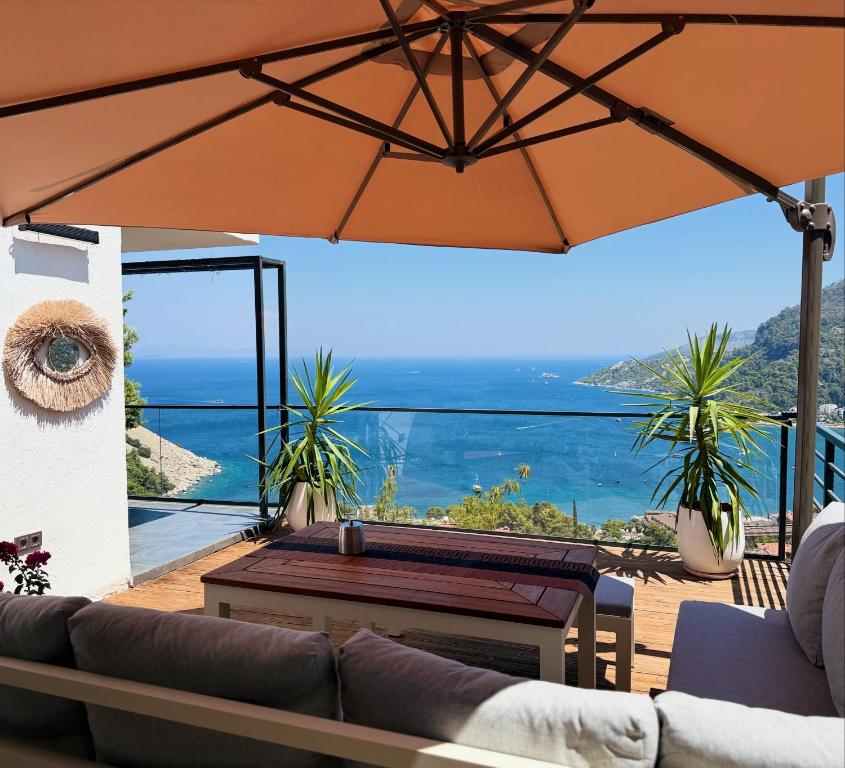 a patio with a table and an umbrella at Mavinin ve Yeşilin dansı, Panoramik manzara, 75m2 in Marmaris
