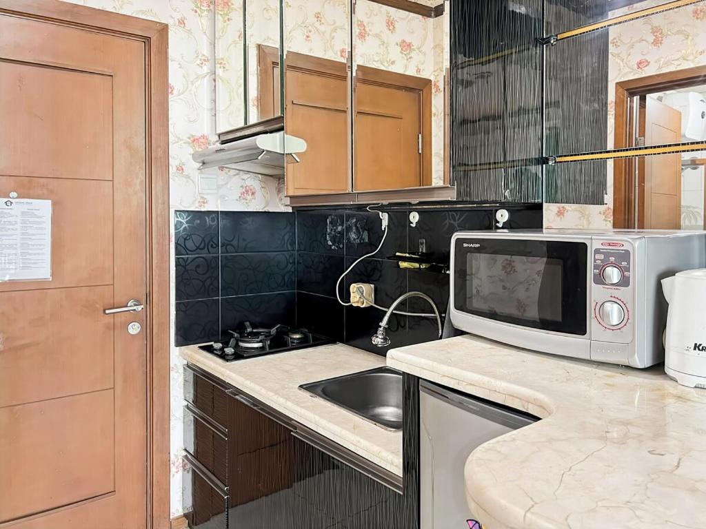 a kitchen with a sink and a microwave at Strategic Thamrin Executive Apt Pool, Gym Wi-Fi in Jakarta
