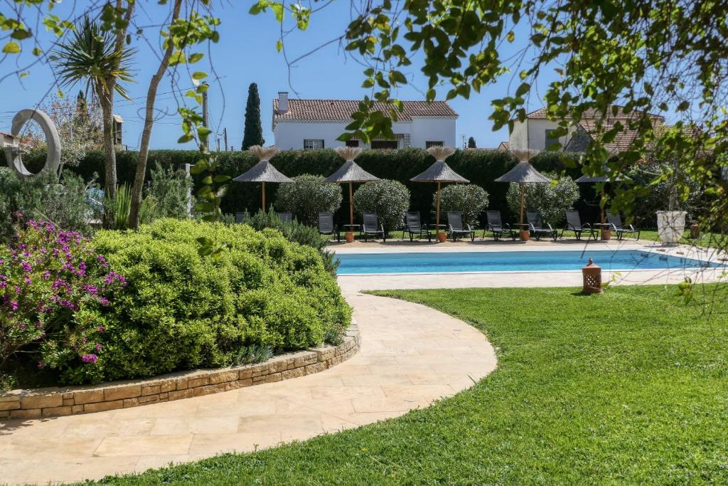 アルルにあるLogis Hôtel Le Rodinのスイミングプールと茂みのあるリゾート