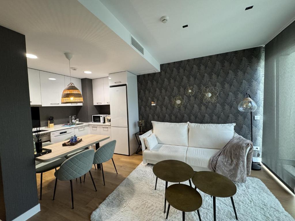 a living room with a couch and tables and a kitchen at A&R Suite Ejecutiva Montes de Oca in San Sebastián de los Reyes