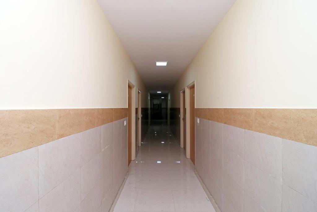 an empty hallway with doors and tile walls at Capital O Crosswind Gold in Indirapuram