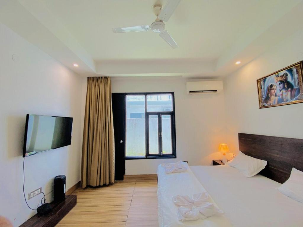 una camera da letto con un letto e una TV a schermo piatto di Rudra inn Peaceful 3BHK Villa near All Mandirs Vrindavan a Vrindāvan