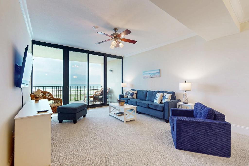 a living room with a blue couch and a ceiling fan at Holiday Isle 618 in Dauphin Island