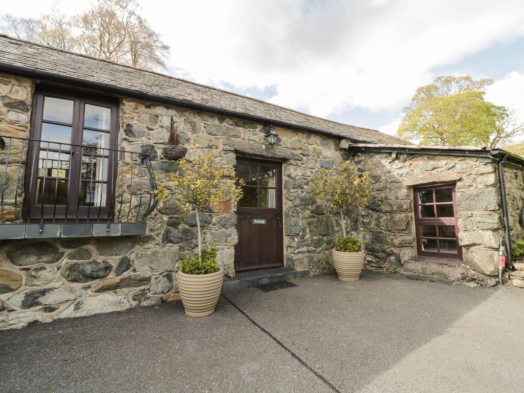 a stone house with two potted plants in front of it at Cyffdy Cottage - Arenig in Bala