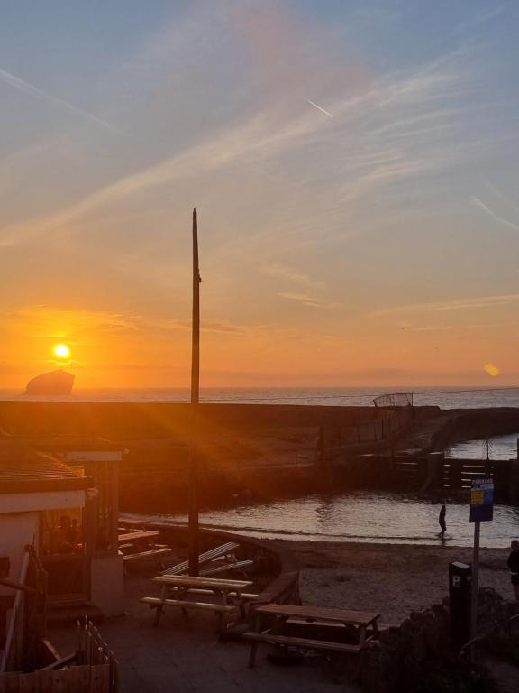 a sunset on the beach with the sun setting at Sandy Paws in Portreath