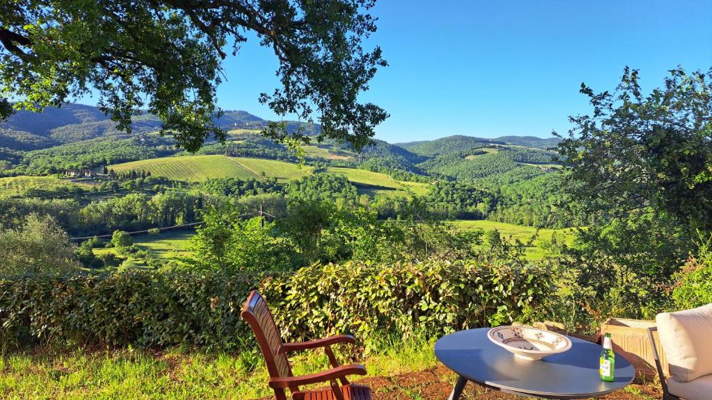 a table and chairs with a view of the hills at Appartamento Holly House in Radda in Chianti