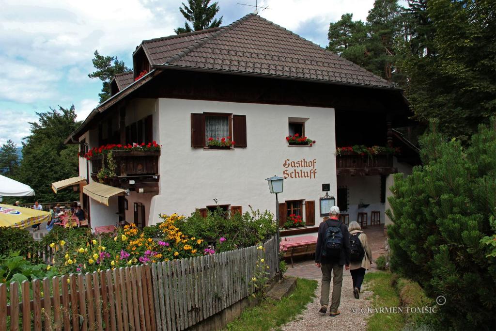 un hombre y una mujer caminando delante de una casa en Gasthof Schluff en Soprabolzano