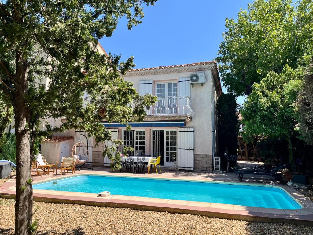 a villa with a swimming pool in front of a house at Villa Perpignan avec piscine - Route des plages in Perpignan