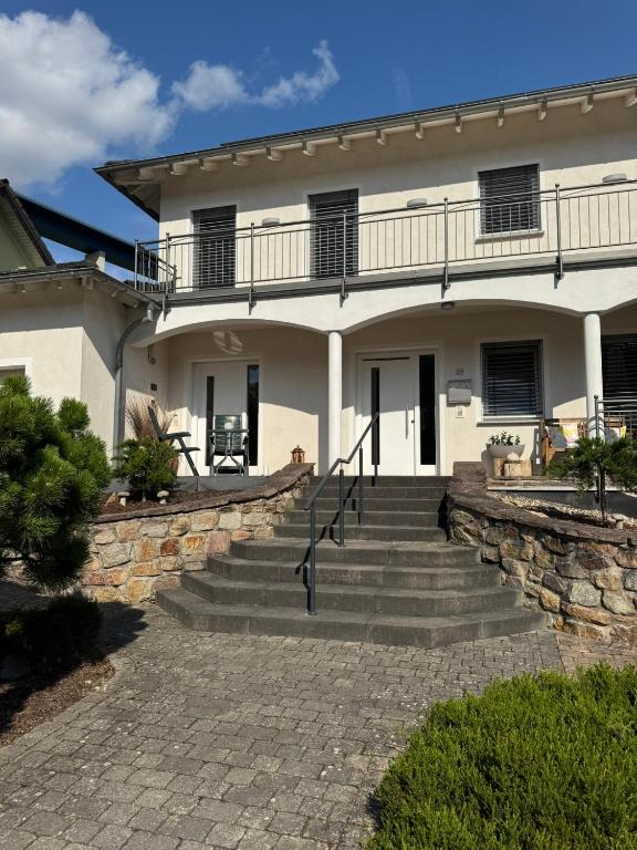 a large white house with stairs in front of it at Moselgold Apartment in Zeltingen-Rachtig
