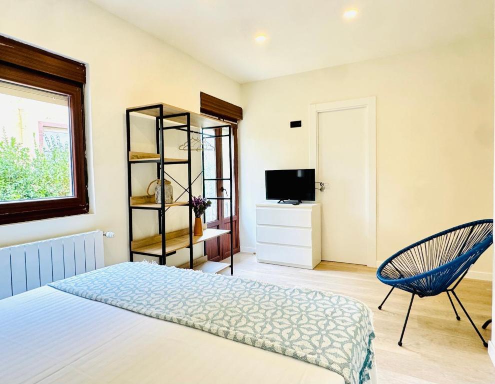a bedroom with a bed and a chair and a television at Villa Olas y Llamas in Santander