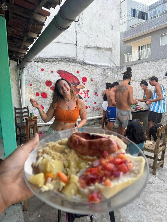 a woman holding a plate of food on a table at Casa Maria Flor Guest House in Itacaré