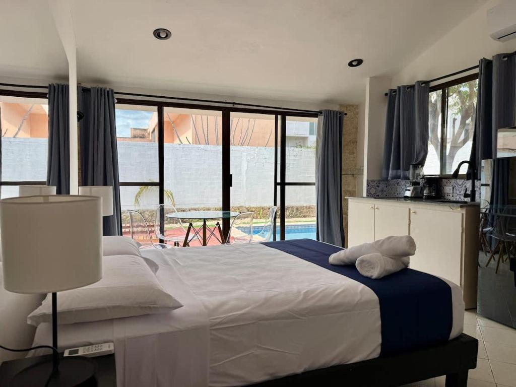 ein Schlafzimmer mit einem großen Bett und einem großen Fenster in der Unterkunft Hermoso y brillante alojamiento con piscina in Mérida