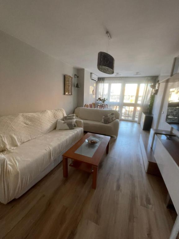 un salon avec un canapé blanc et une table dans l'établissement Amplio apartamento, playa, tren, à Malaga
