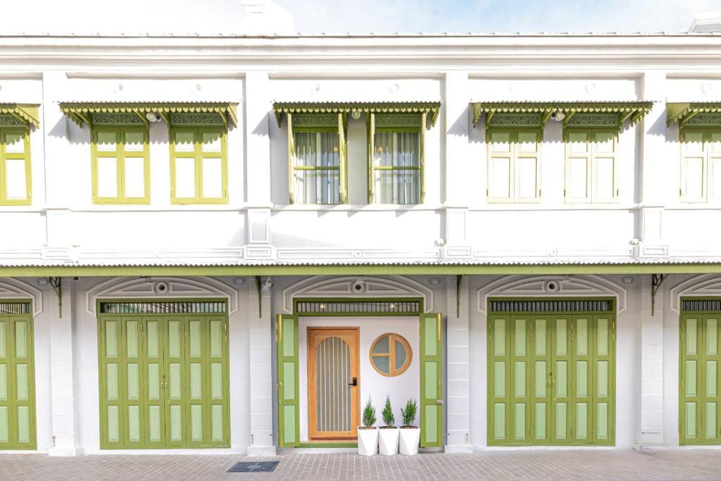 - un bâtiment blanc avec des portes et des fenêtres vertes dans l'établissement Kraft Haus, à Khlong San