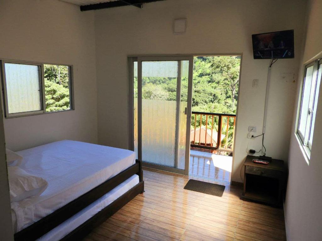a bedroom with a bed and sliding doors with a balcony at El Tucán Ecolodge Manaure in Manaure