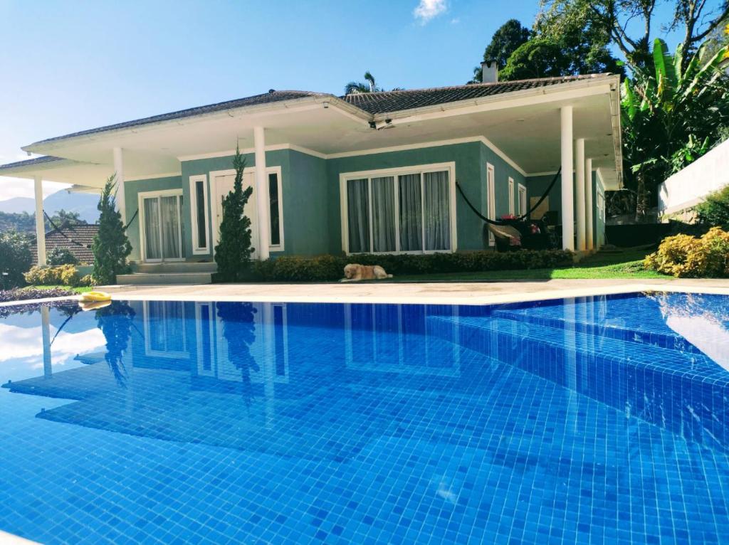 a swimming pool in front of a house at Quarto-Suíte Serra Petrópolis in Petrópolis