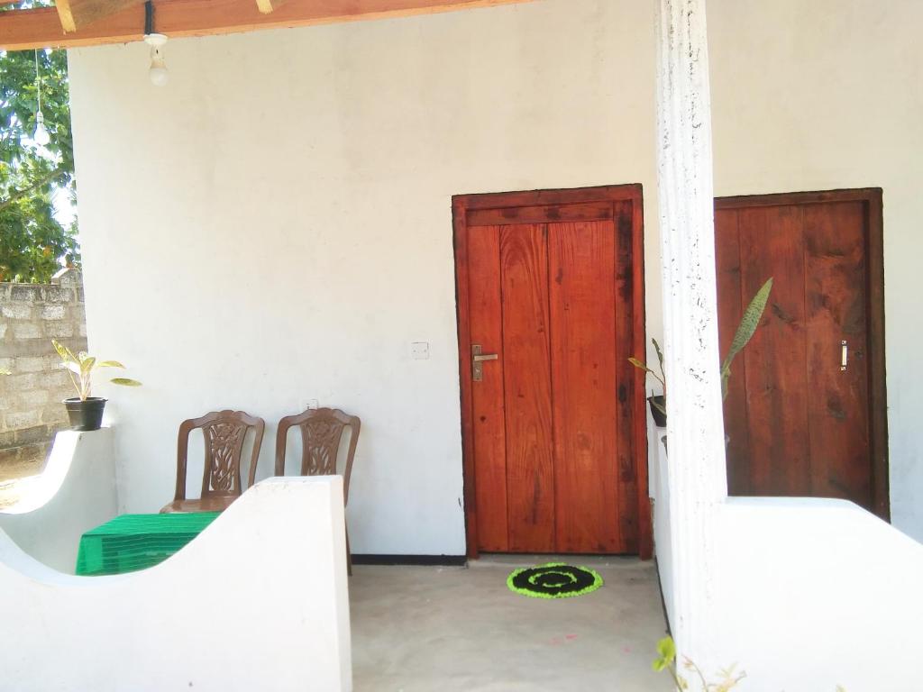 a room with two chairs and a wooden door at Fr Resort in Arugam Bay