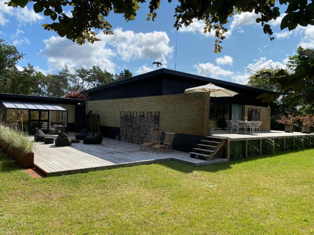 a backyard with a deck and a building with a patio at Cottage With 400 M To The Water And The Marina in Østerby Havn