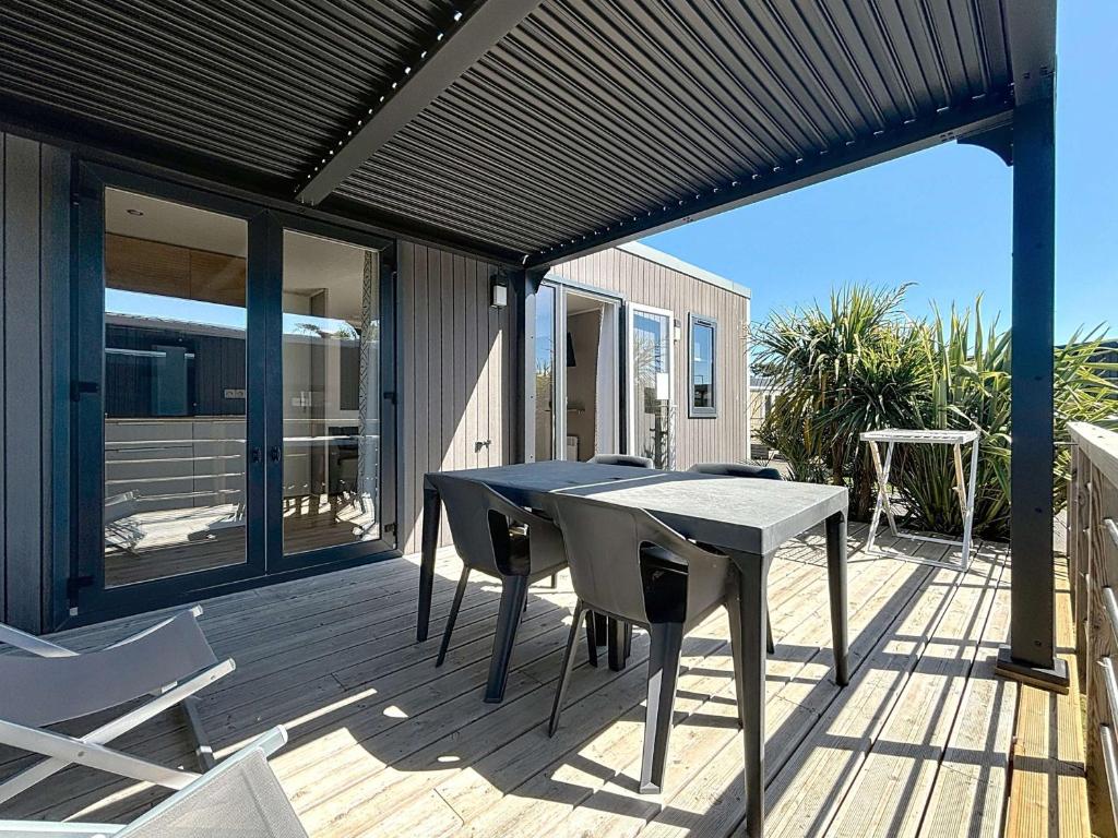 un patio avec une table et des chaises sur une terrasse dans l'établissement Mobil-home 4* Grand Confort, 200m plage, piscine, fitness, parking, ménage inclus, Wi-Fi gratuit - FR-1-361A-75, à Jullouville
