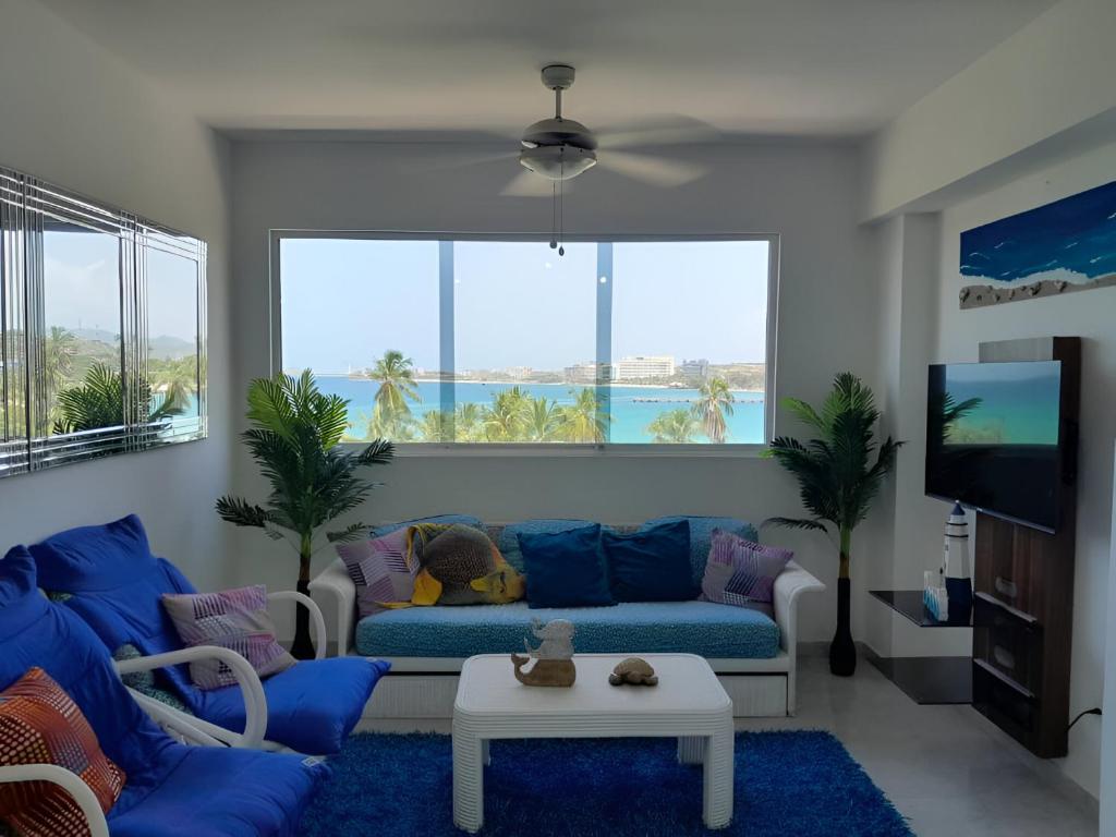 uma sala de estar com um sofá azul e uma grande janela em Apartamento con vista al mar em Pampatar
