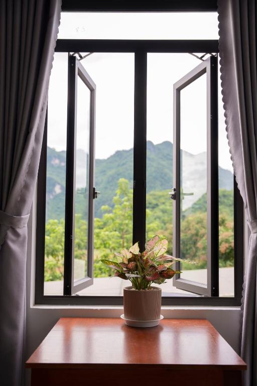 a vase of flowers on a table in front of a window at Bao An Homestay Mai Chau in Mai Châu