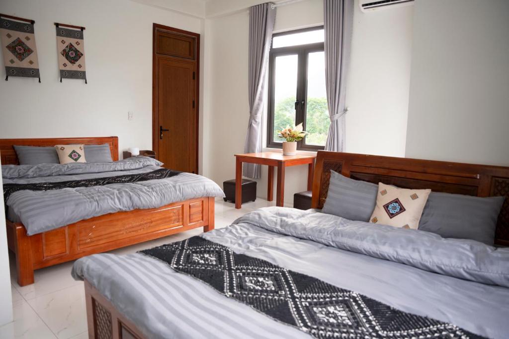 枚州县Bảo An Homestay的一间卧室，配有两张床和一扇窗户