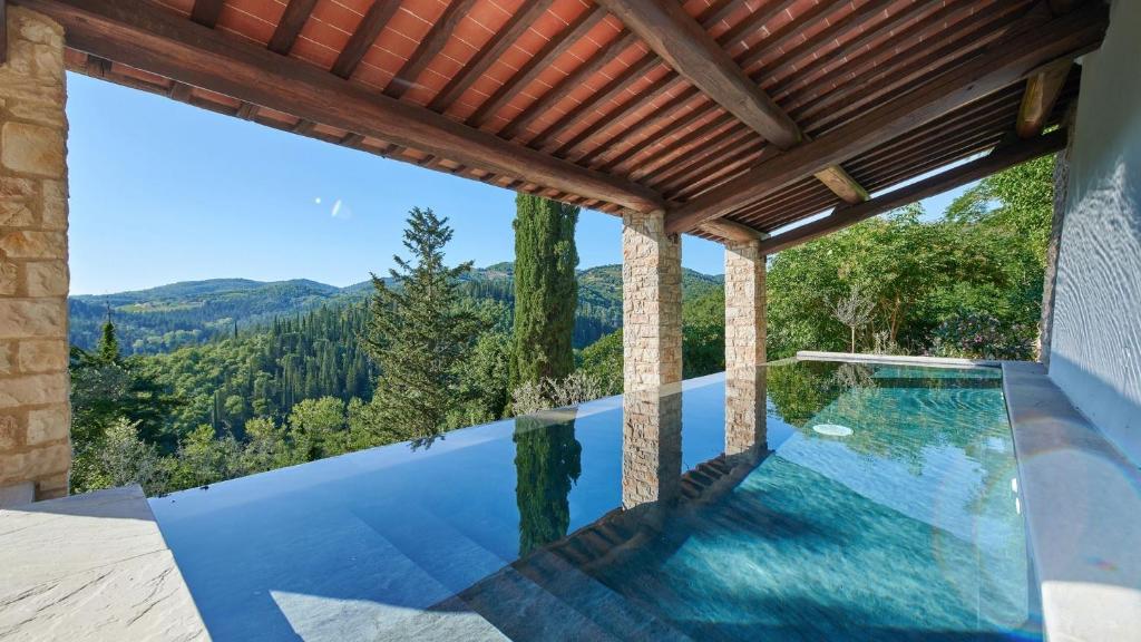una piscina infinita en una casa con techo de madera en Villa Altho, en Gaiole in Chianti