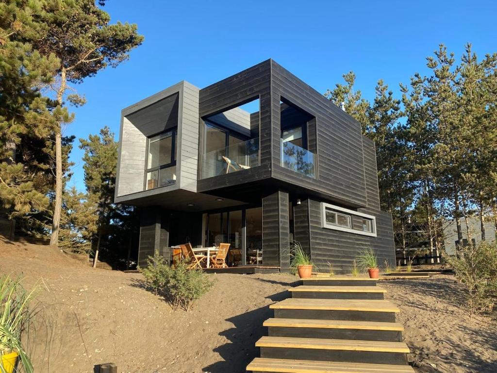 a black house on a hill with stairs at Calm and beautiful beach in Pichilemu