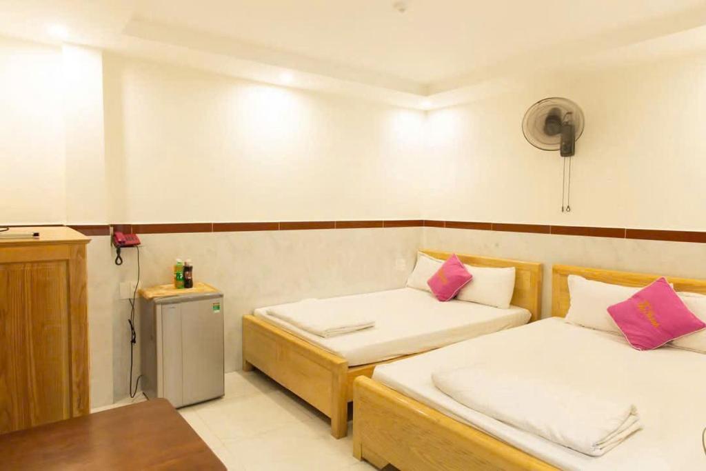 Una pequeña habitación con dos camas y una nevera. en Thị Thành Hotel, en Vung Tau