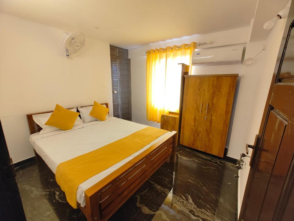 une chambre avec un lit avec des oreillers jaunes et une fenêtre dans l'établissement Rajdhani Hospitality, à Kazhakuttam