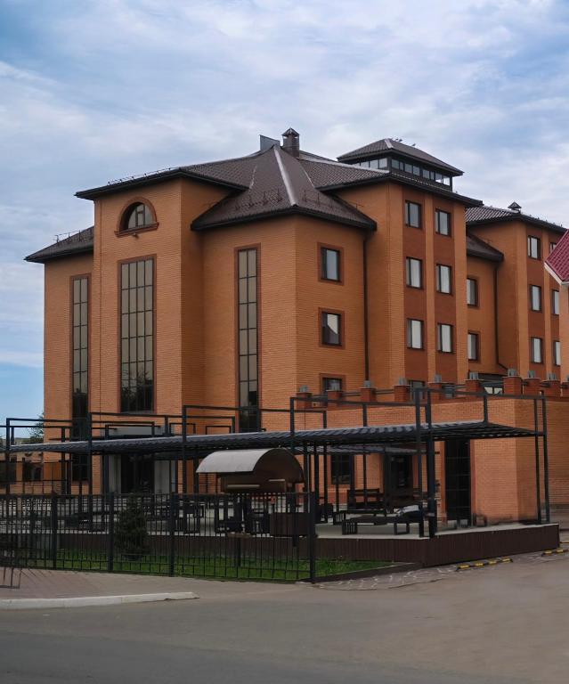 a large brick building with a fence in front of it at Hotel Gloria Deluxe in Borovoye