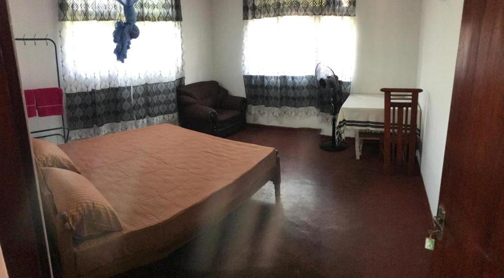 een slaapkamer met een bed, een bank en 2 ramen bij Selene House in Hikkaduwa