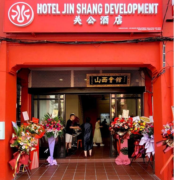 a red hotel with people standing outside of a building at Guan Gong Hotel Jin Shang Development Jonker Street in Malacca