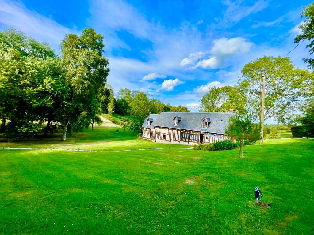 an old barn on a green field with a house at Séjour à la campagne près de Camembert dans le bocage normand in Les Champeaux