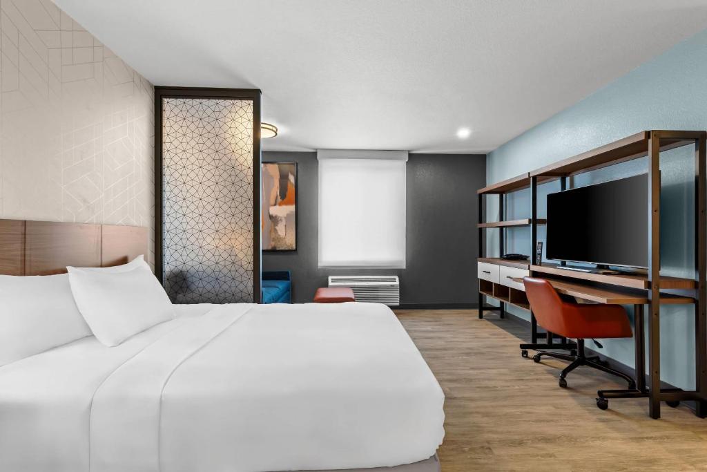 a bedroom with a bed and a desk and a tv at Everhome Suites Temecula Wine Country in Temecula