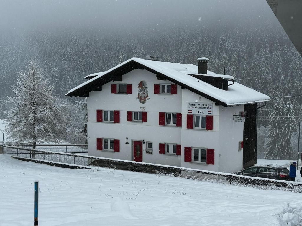 a white building with red doors in the snow at Apartment in Sankt Gallenkirch near Ski Slopes in Sankt Gallenkirch