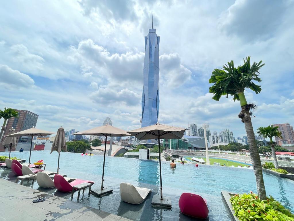 a pool with chairs and a tall building in the background at Blue Haven Apartment at Opus Residence Kuala Lumpur in Kuala Lumpur