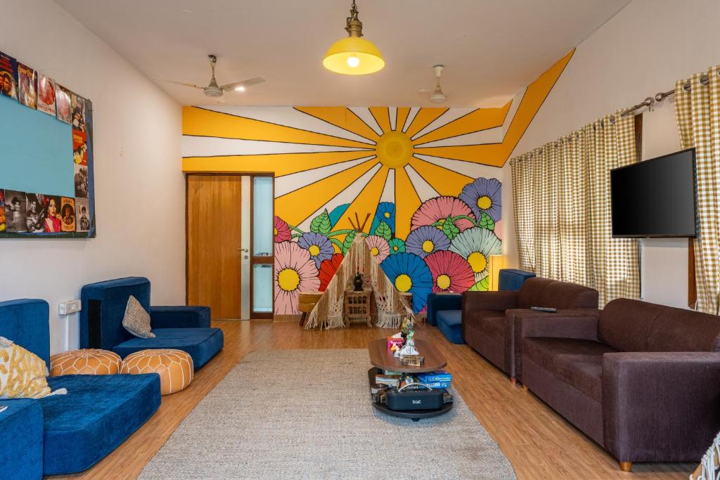a living room with blue couches and a mural at Whiite Panda - Backpacker Hostel in Delhi Greater Kailash in New Delhi